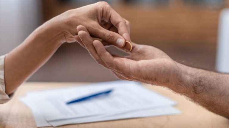 Woman handing ring to man with divorce papers
