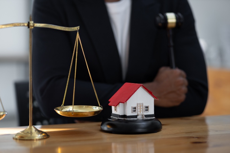 house on a gavel block with scales of justice nearby