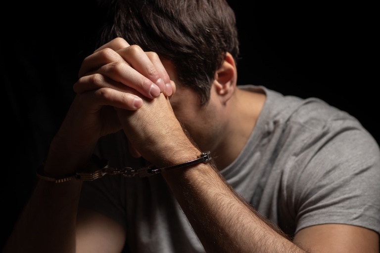 man in handcuffs resting his head in hands