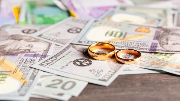 An old, crumpled dollar and wedding rings