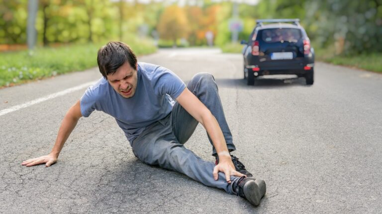 Injured man on road in front of a car