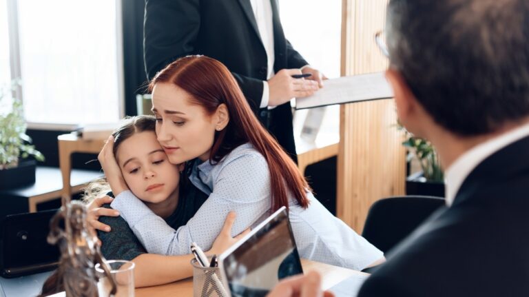 sad woman hugs little upset girl sitting in lawyer's office