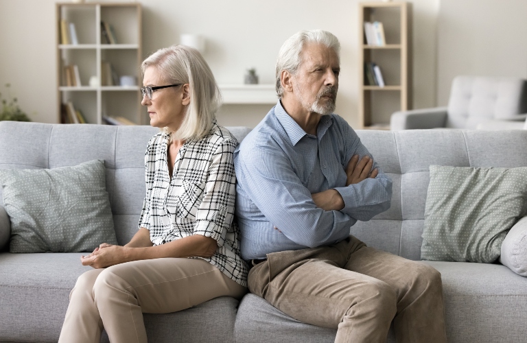 Annoyed ignoring senior couple sitting on home couch back to back