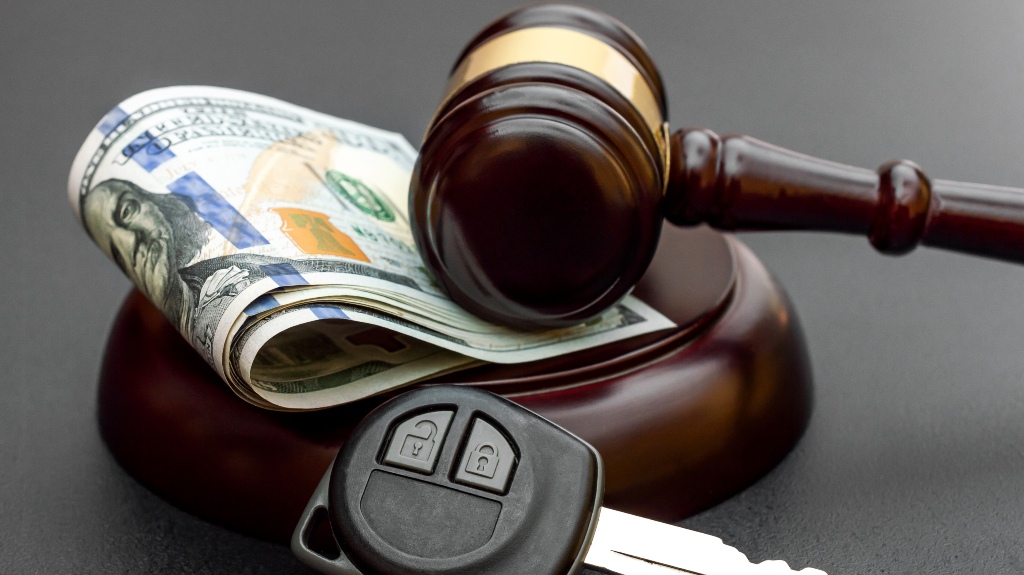 Judge's gavel with car key and money on black