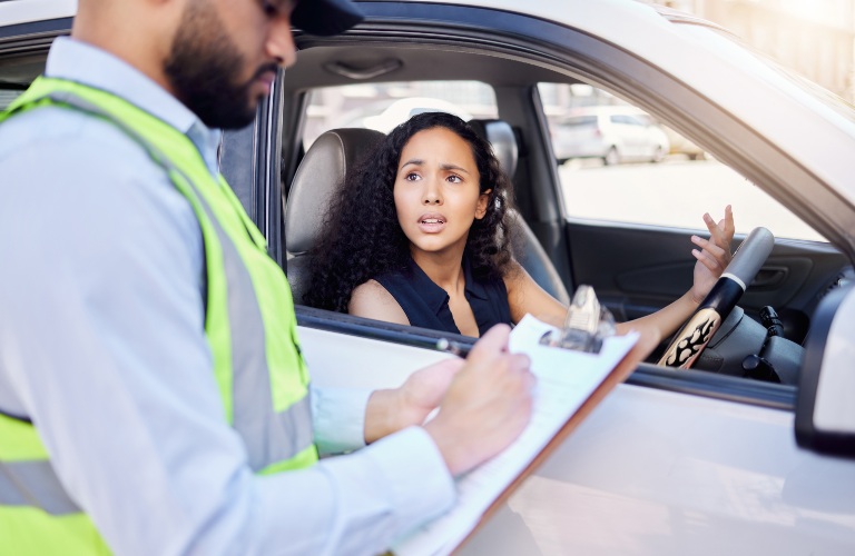 woman and traffic officer with ticket by car for speeding
