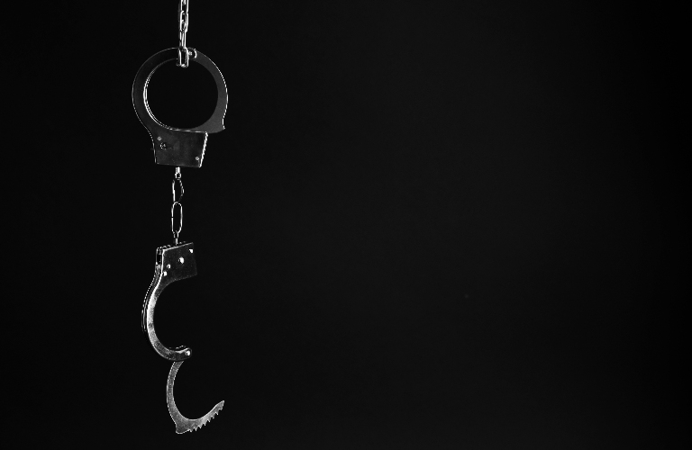 Classic chain handcuffs hanging on black background