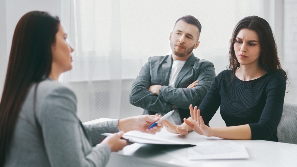 A couple is sitting at a table in an office, meeting with a lawyer