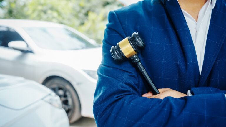 lawyer holding a wooden gavel, stand in front of a car