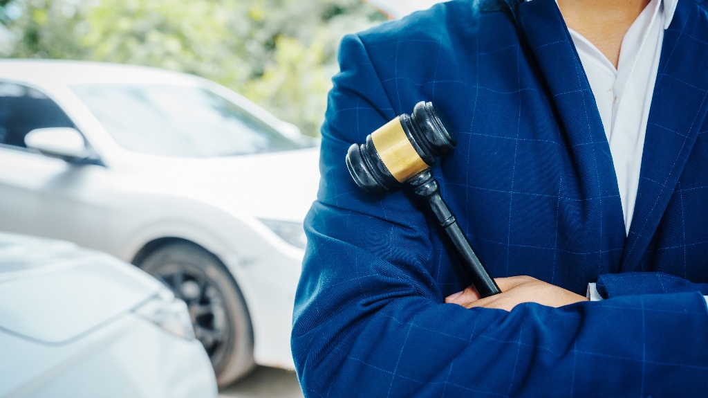lawyer holding a wooden gavel, stand in front of a car