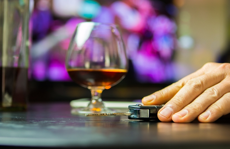 man drinking whisky at bar and taking car key from table