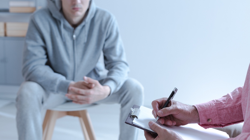 young troubled man sitting on a chair in a blurred background