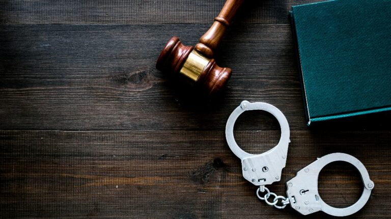 Metal handcuffs near judge gavel and law book