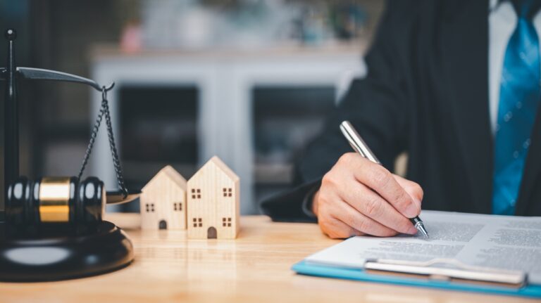 Lawyer is working with documents near two wooden house models