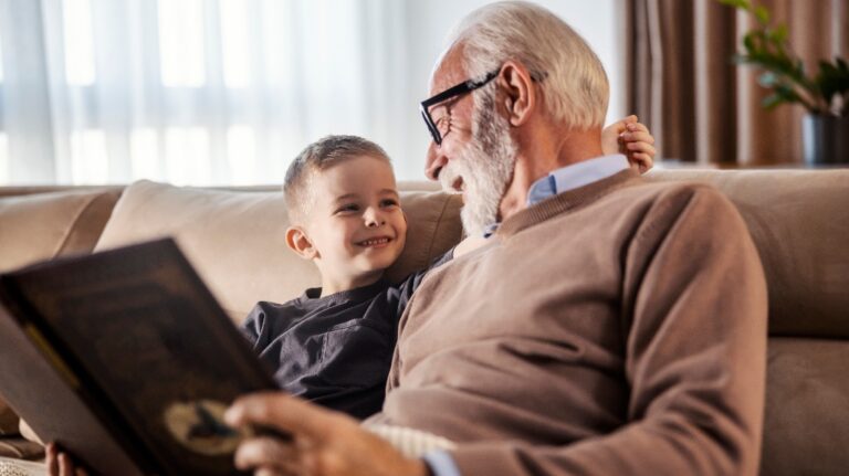 grandfather is reading a book to his grandchild at home