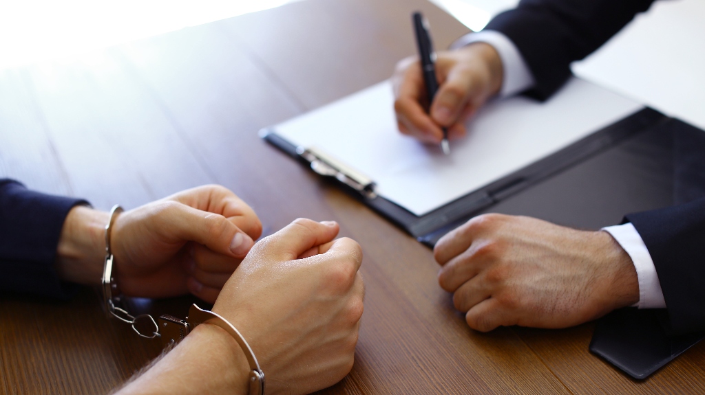 Police officer interrogating criminal in handcuffs
