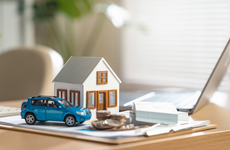 A blue car is on a table next to a house