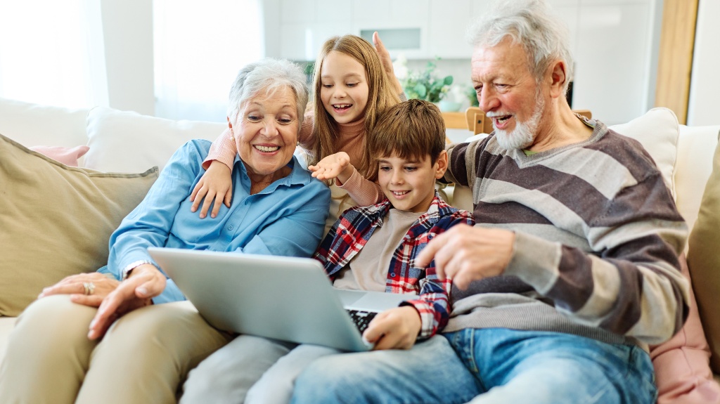 Family grandparents and grandchildren having fun at home using laptop